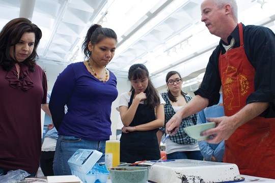 Four international students at INTO The University of Alabama at Birmingham participate in cooking class with instructor in bright, white classroom.