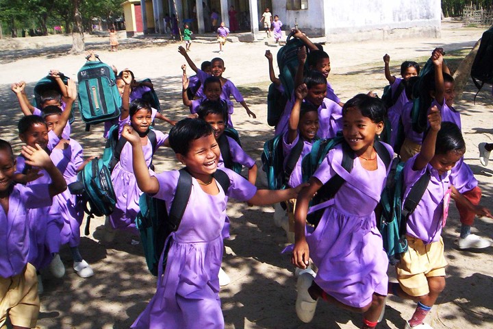 Young schoolchildren benefiting from INTO Giving philanthropy project run through street and grin, wearing purple dresses and shirts.