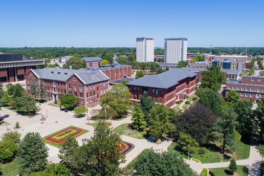 Aerial view of brick buildings and residence towers on Illinois State University campus in Bloomington, IL, on sunny day.