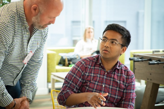 International student sits at desk and speaks with instructor during INTO Summer Employment Boost program in London, UK.