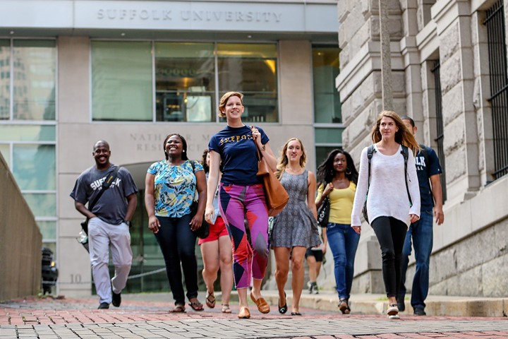 International students from INTO Suffolk University walk together down brick road in Downtown Boston, in front of Nathan R. Miller Residence Hall.