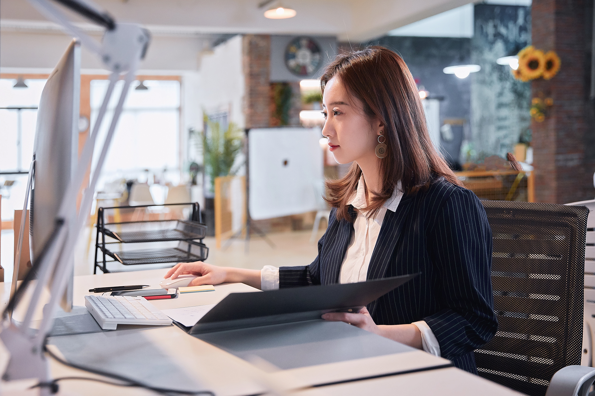 International education professional works at computer in sun-filled office.
