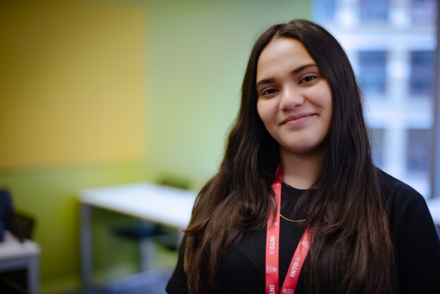 Aliya from Pakistan, a business and economics student at INTO, City University of London, smiles in a classroom.