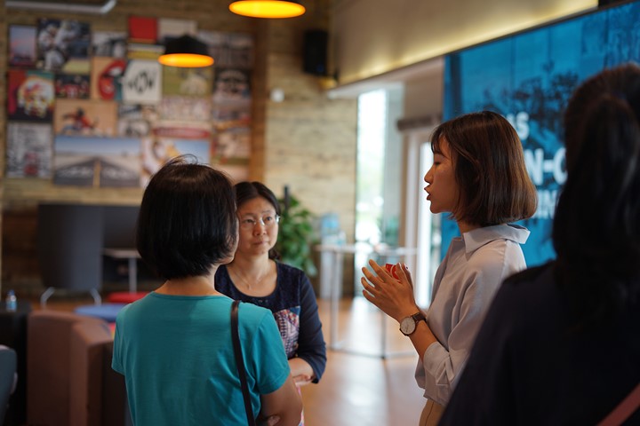 Education adviser talks to prospective international student and parent at INTO University Access Center in Ho Chi Minh City, Vietnam, with art wall in background.