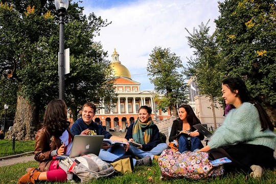 Group of international students from INTO Suffolk University sit and work on lawn in front of Massachusetts State House in downtown Boston. 